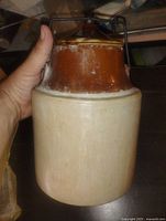 Side view of crock showing two-tone glaze and iron handle