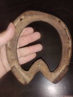Front of iron horseshoe held in hand showing size and nail holes