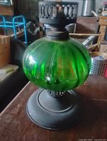 Full view of green glass oil lamp on metal base