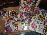 Overview of open box showing binder pages filled with hockey cards and loose cards underneath