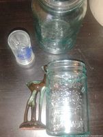 Two mason jars, shot glass, metal deer visible
