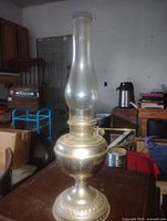 Full view of brass-tone metal oil lamp with chimney