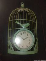 Front view of metal birdcage clock showing cage design, bird ornament and clock face