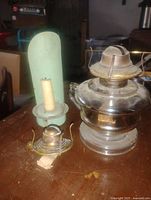 Group view of glass oil lamp, green candle holder with candle, and small burner on tripod