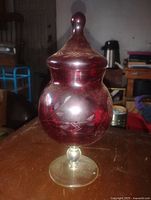 Front view of ruby red glass covered dish showing etched leaf motifs and clear pedestal base