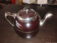 Side view of glazed stoneware teapot with lid