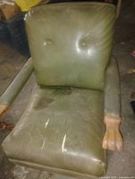 Front view of green leather spring chair showing overall form and wear