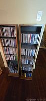 Two tall narrow wood cabinets filled with CDs