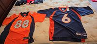 Two Denver Broncos Reebok jerseys laid out, numbers 88 and 6 visible