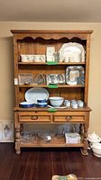 Full view of two-piece wooden display cabinet with shelves and drawers
