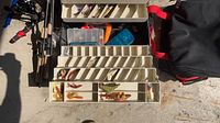 Four rods, tackle box open showing trays of lures, canvas bag