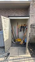 Overall view of garden shed with assorted long-handled tools