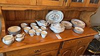 Overall view of Wedgwood china set on wooden hutch