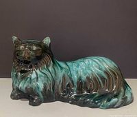 Front view of Blue Mountain Pottery reclining cat figurine showing green/black drip glaze and facial details
