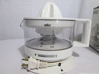 Juicer fully assembled showing pitcher, reamer, Braun branding, cord wrap