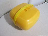Closed yellow plastic picnic carrier showing exterior and handle