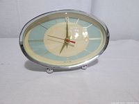 Front view showing oval dial, hands, color scheme, feet