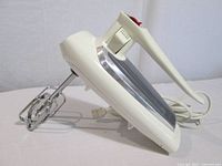 Side view of cream GE hand mixer showing beaters and cord