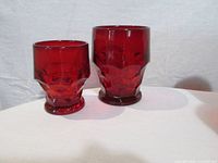 One small and one large red faceted tumbler side by side showing colour and size difference