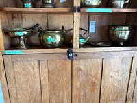 Shelf showing brass footed bowl with ladle, brass pot, brass kettle