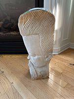 Side view of carved stone male head bust showing textured hair, facial features and base condition