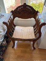 Full view of carved wooden armchair showing frame and plywood seat