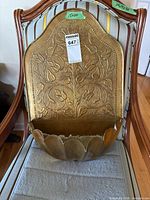Embossed brass wall pocket planter front view on chair