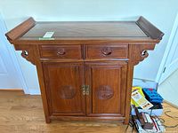 Front view of Asian style accent cabinet showing drawers, doors, carved medallions