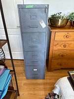Full view of grey 4-drawer filing cabinet beside wooden chest