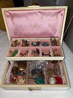 Open jewelry box showing top compartment and lower tray filled with assorted vintage costume jewelry pieces
