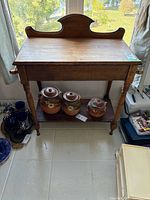 Full view of wooden dry sink with backsplash, legs and lower shelf