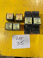 Eight sealed Napco boxes of hydraulic grease fittings on yellow surface