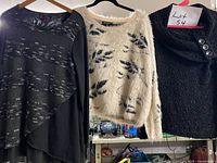 Three sweaters hanging side by side showing front designs