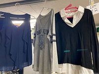 Three tops on hangers: navy sleeveless blouse, grey Brooklyn tee, black sweater with white collar