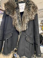 Front view of black Novelti coat with faux fur collar, studded pockets, and fur hem
