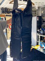 Front view of black leather chaps on hanger