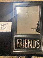 Front view of black framed mirror showing FRIENDS cut-out