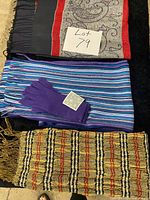Three scarves laid flat with gloves on striped scarf
