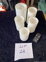 Overview of five white pillar candles with remote