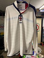 Front view of white England Umbro long-sleeve jersey on hanger