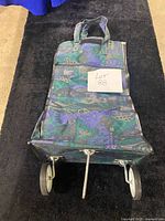 Front view of wheeled shopping cart showing fabric bag pattern, wheels and support stand