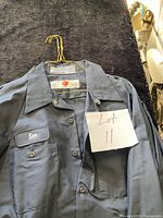 Front view of one GK work shirt on hanger showing name patch, collar, buttons and color