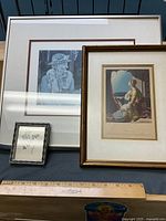 Three framed artworks on table: Susan King etching, G. Banks engraving, small botanical print