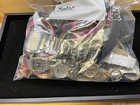 Front view of sealed bag showing assortment of wristwatches and straps