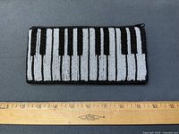 front view of beaded piano keyboard clutch with ruler for scale