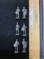 Six metal knight figurines beside ruler showing height