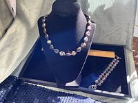 Necklace on display bust with bracelet beside