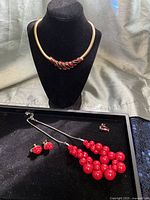 Overview showing collar necklace on bust, bead necklace, clip-on earrings, rhinestone ring