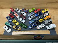 Full lot overview showing 26 die-cast vehicles with ruler for scale