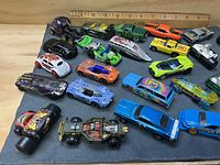 Overhead view of full lot of die-cast vehicles on grey cloth with ruler for scale